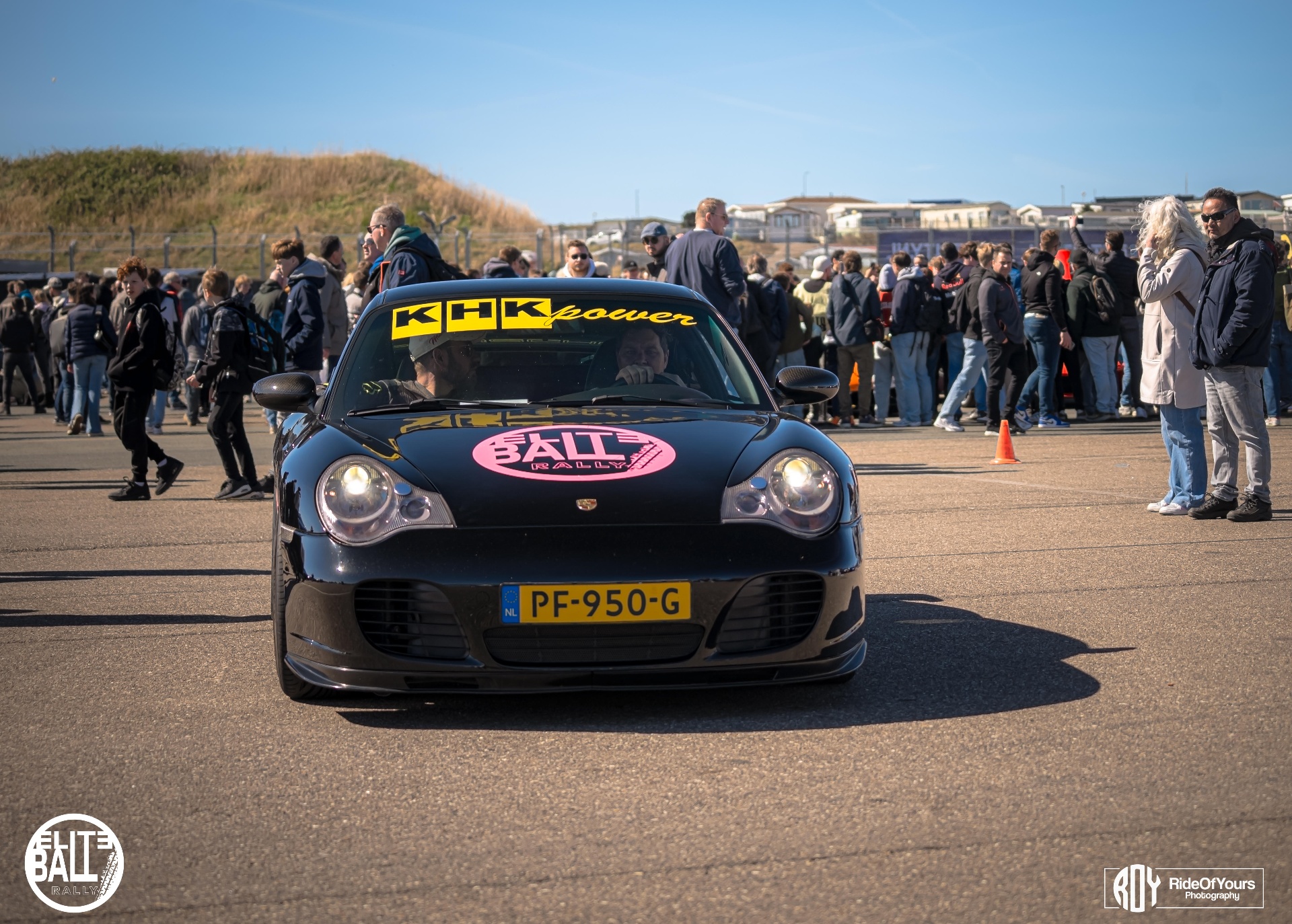 Zwarte Porsche 911 met Eliteball Rally sticker tussen het publiek
