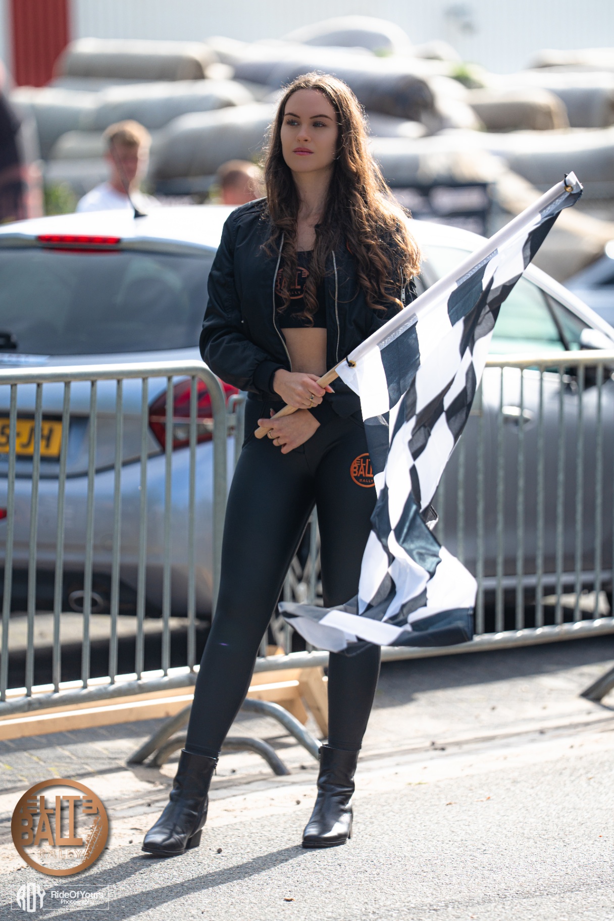Grid girl met finishvlag voor zilveren cabrio tijdens Eliteball Rally