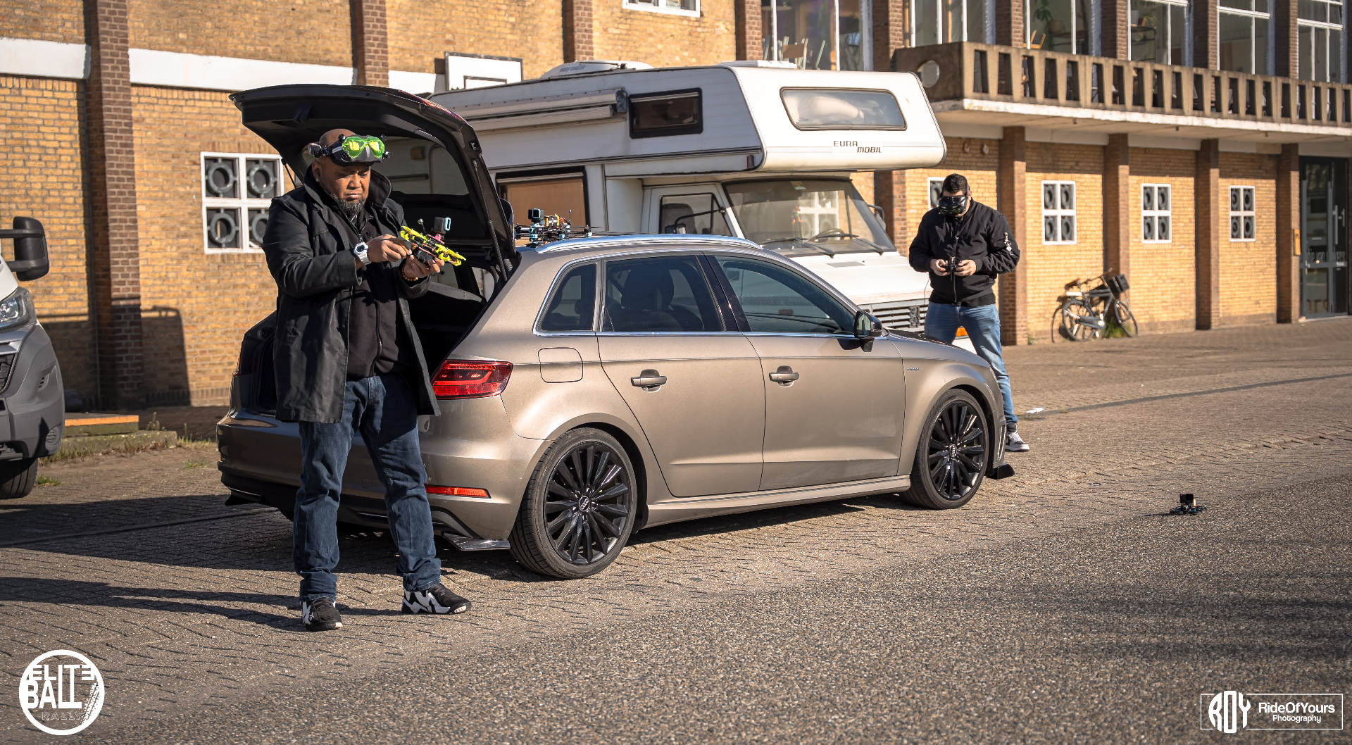 Dronecrew naast Audi stationwagen tijdens Eliteball Rally