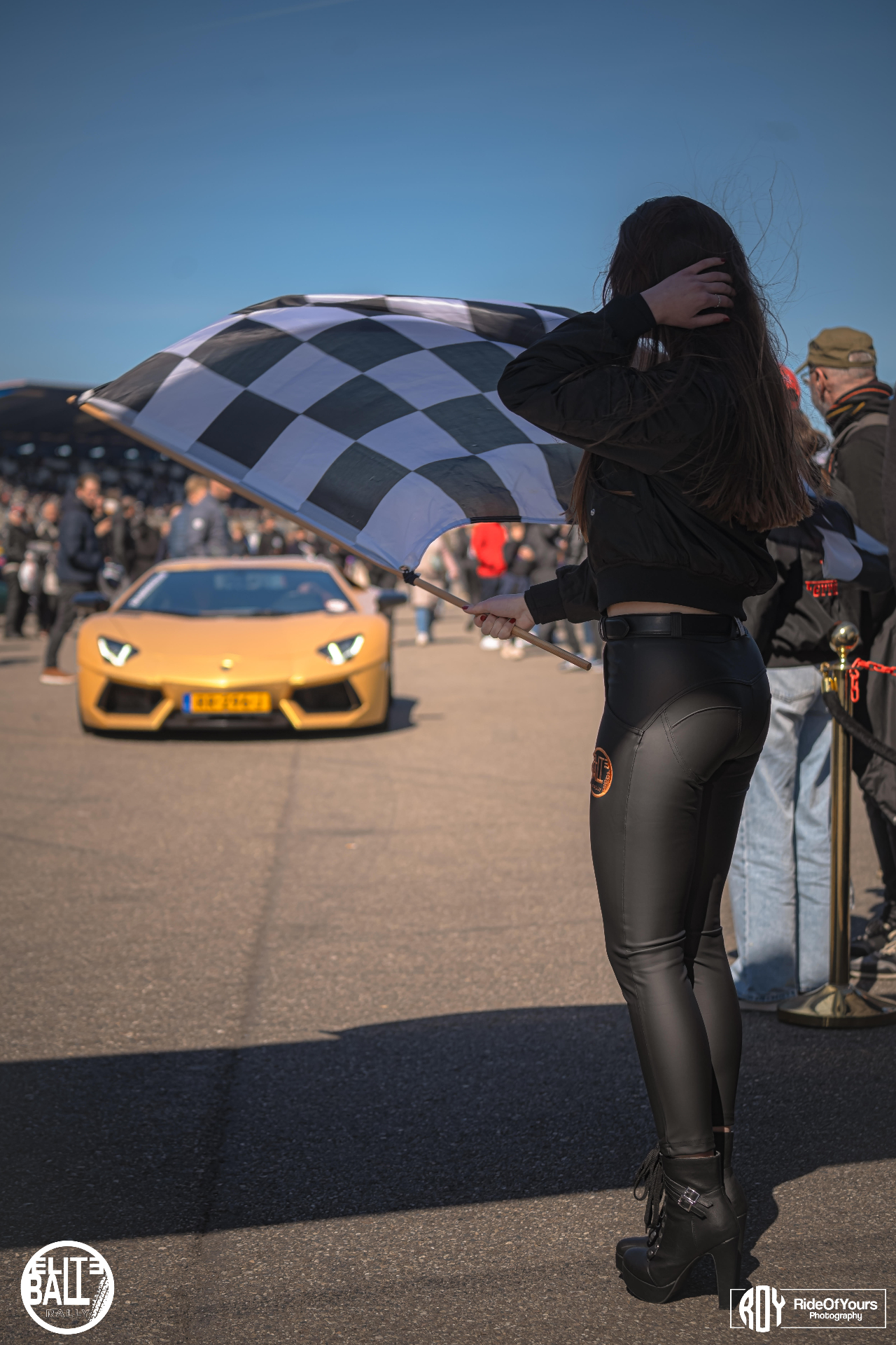 Grid girl met finishvlag en gouden Lamborghini Aventador